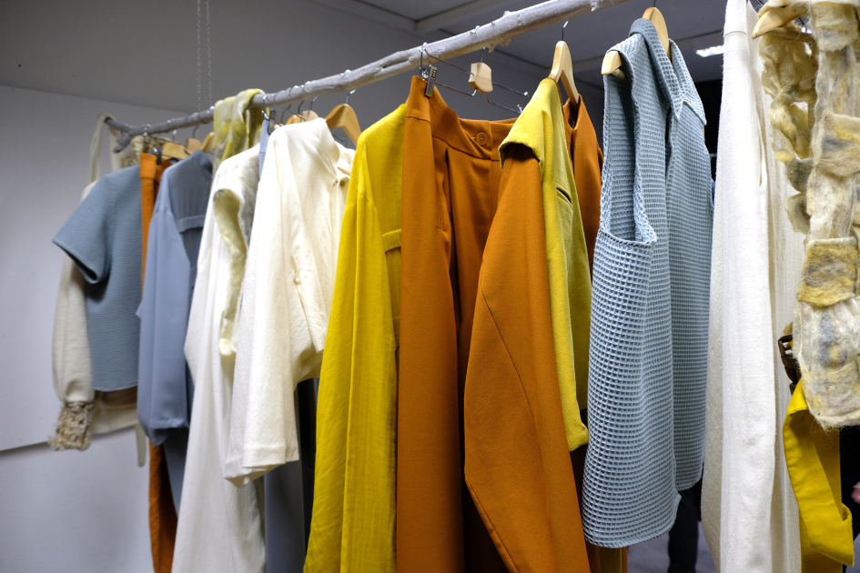 An einer Kleiderstange hängen verschiedene Kleidungsstücke Gelb und Blautönen