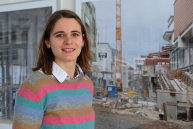 Eine Frau steht vor einem großen Foto auf dem eine Baustelle zu erkennen ist