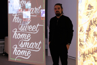 Ein Mann setht zwischen zwei digitalen Leinwänden