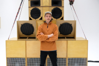 Ein Mann steht mit verschränkten Armen vor großen Lautsprechern