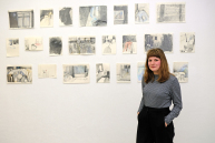 Eine Frau steht vor einer Wand an der Zeichnungen hängen