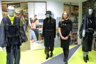 Eine Frau steht zwischen drei bekleideten Schaufensterpuppen