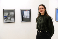 Eine Frau steht vor einer Wand mit eingerahmten Fotografien