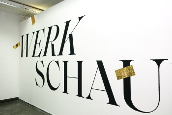 An einer Wand steht in großen Buchstaben das Wort Werkschau.