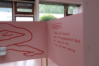 An einer Holzwand steht mit roter Schrift Text.