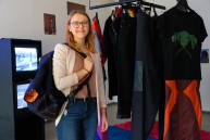 Eine Person hat einen Rucksack auf der Schulter und blickt in die Kamera.