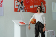 Eine Person hat einen Ball unter dem Arm und blickt in die Kamera.