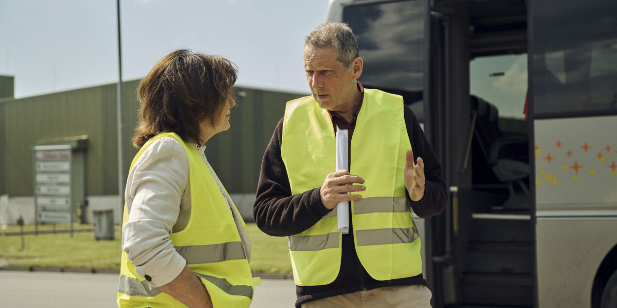 Professor Johannes Weinig steht mit einer anderen Teilnehmerin der Gruppe von der HSBI vor einer geöffneten Bustür und unterhält sich mit ihr