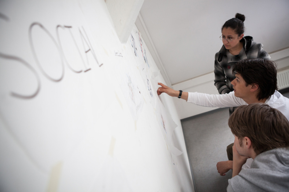 Drei Studierende hocken vor einer Mind-Map.