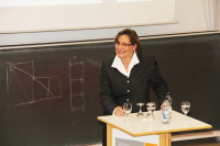 Professorin Mons sthet vor der Tafel und hält ihren Vortrag