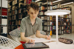 Foto: Nico Niesterok arbeitet in der Bibliothel des Campus Minden an einem Tablet