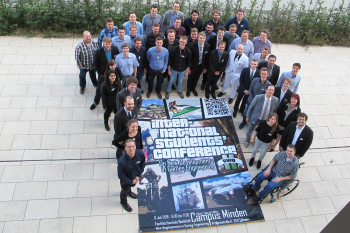 Die Teilnehmer stehen vor dem Banner der Konferenz.