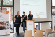 Drei Studentinnen stehen am Rednerpult