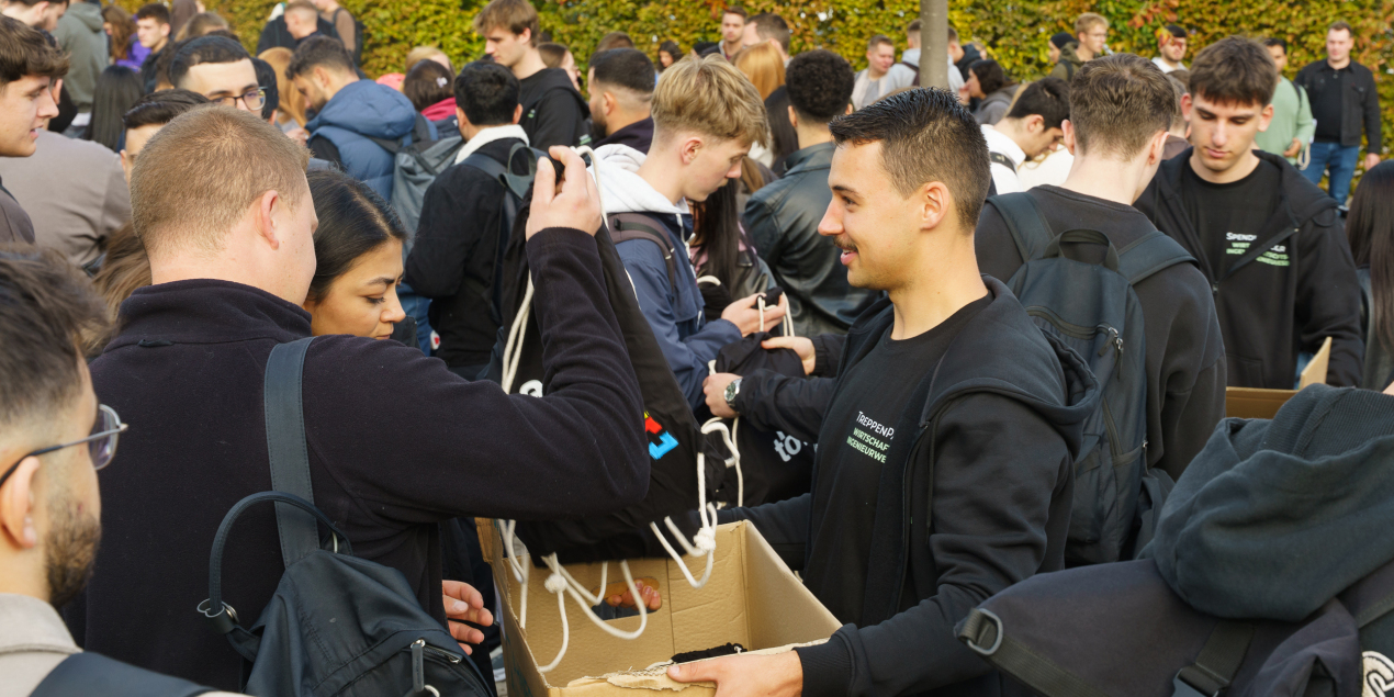 ein Student verteilt Umhängetaschen der Stadt Minden aus einem Karton heraus