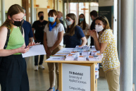 Mehrere Personen stehen an einem Infostand im Hörsaalgebäude