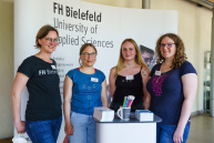 Vier Personen stehen an einem Infostand