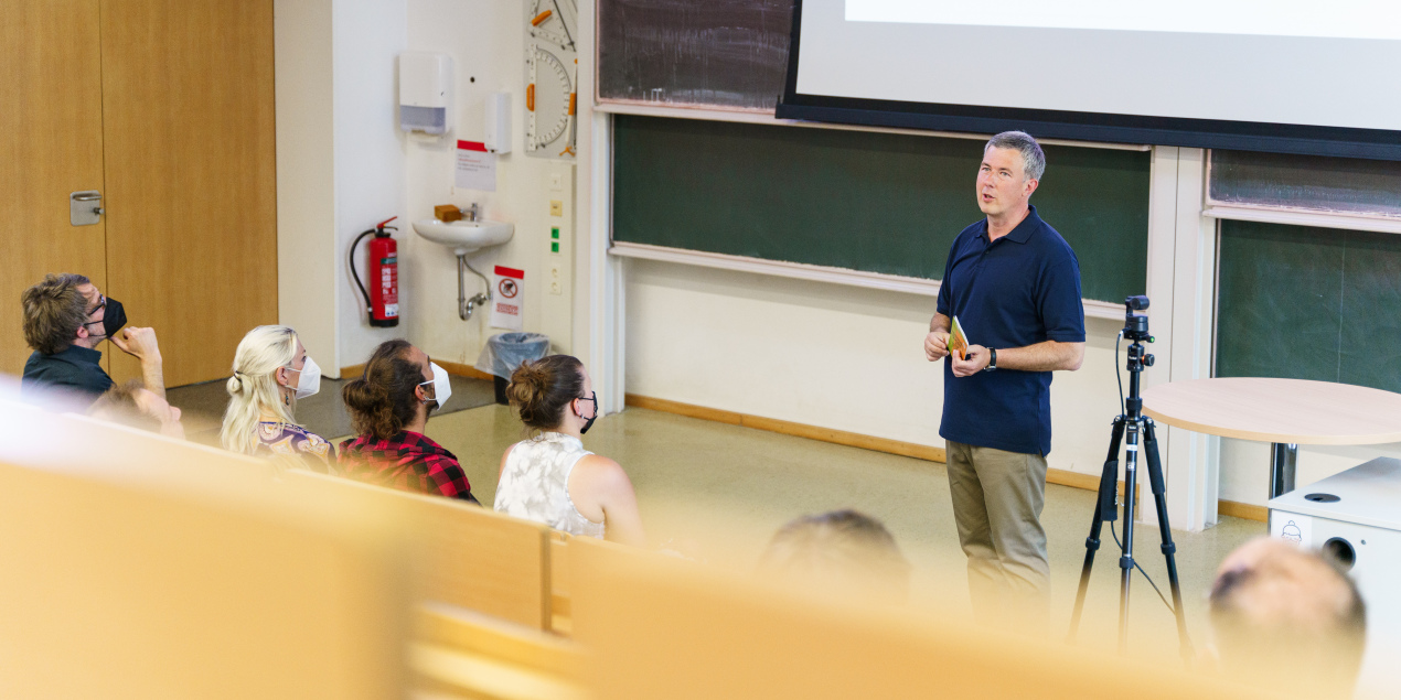 Blick aus den Sitzreihen eines Hörsaals auf den Referenten