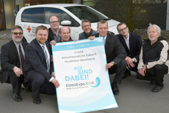 Mitglieder es Projekts hocken vor einem Eletroauto.