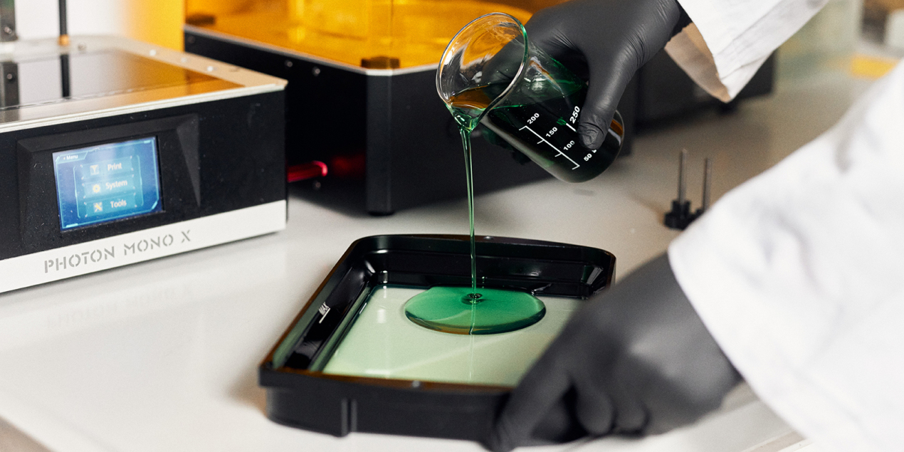 Timo Grothe gießt das grüne Kunstharz in ein schwarzes Becken mit Glasboden.