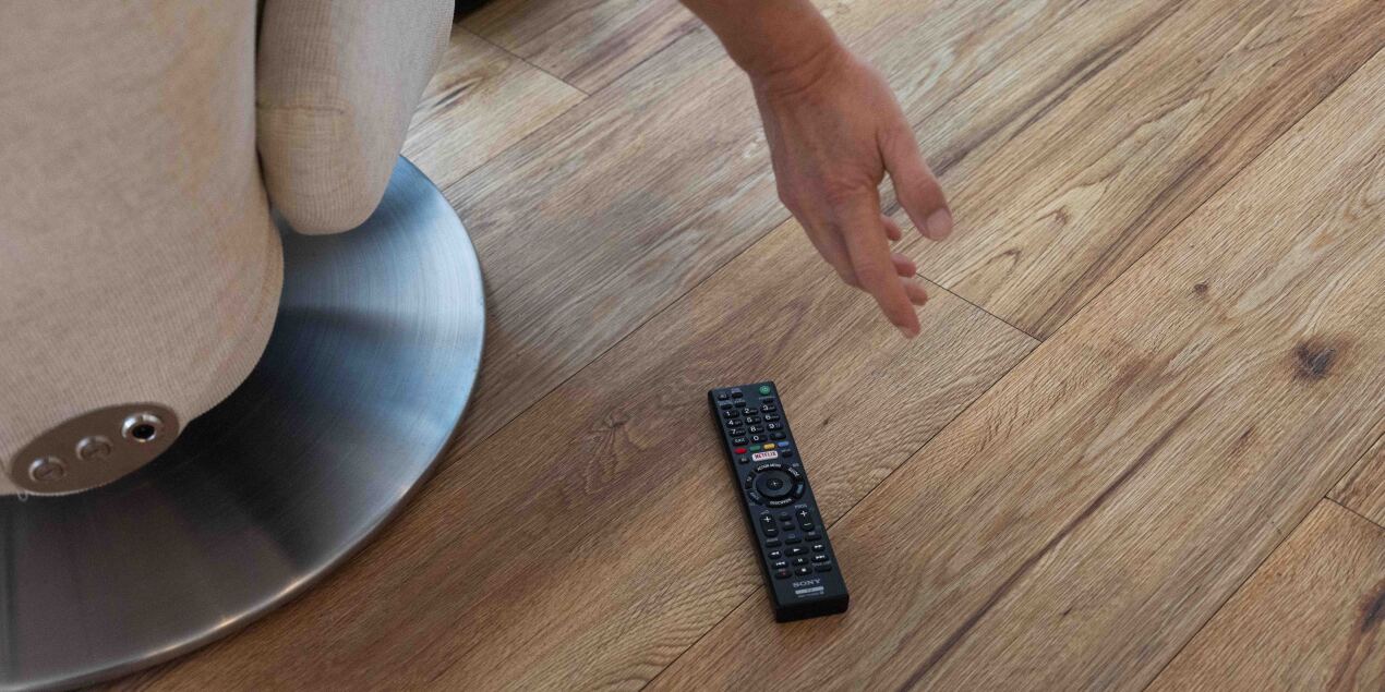 Foto: Eine Person liegt bewusstlos in einem Sessel neben ihr liegt eine Fernbedienung auf dem Boden