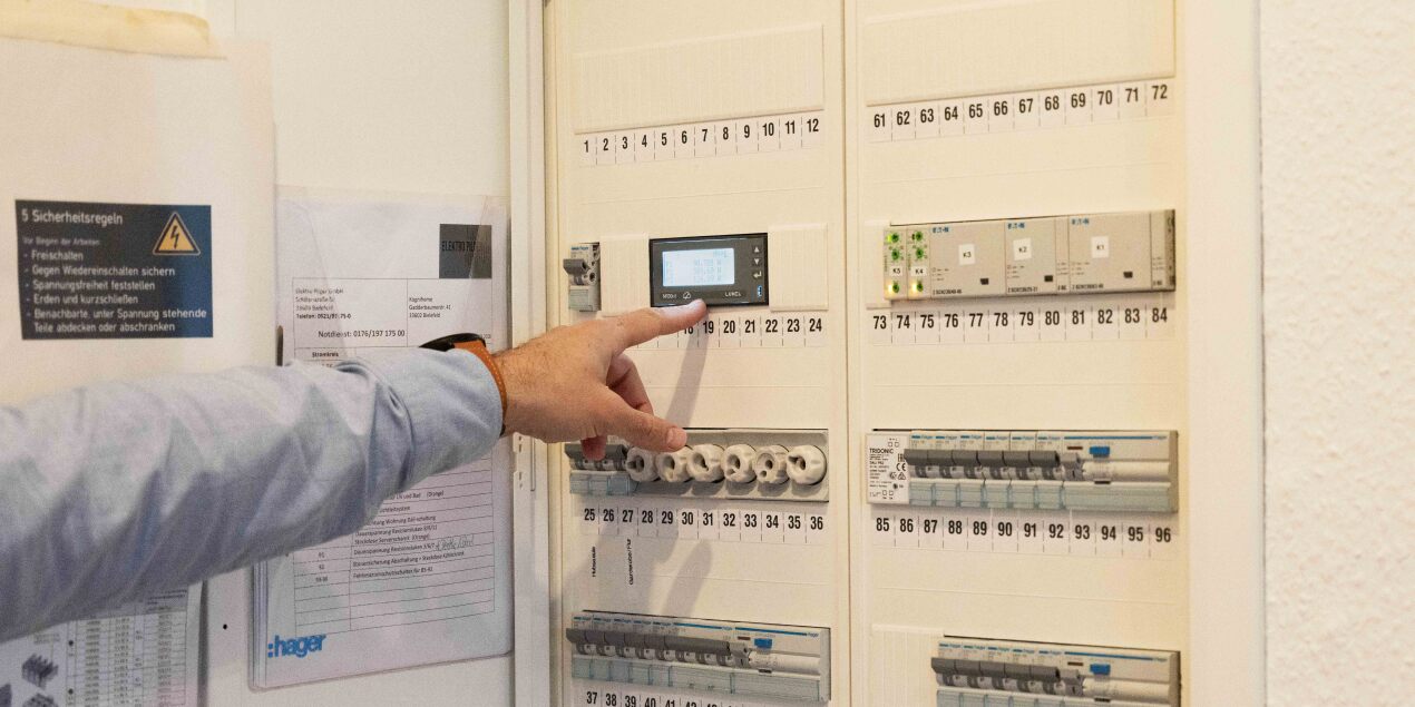 Photo: A finger points to an open electricity cost display which also shows water consumption in the KogniHome
