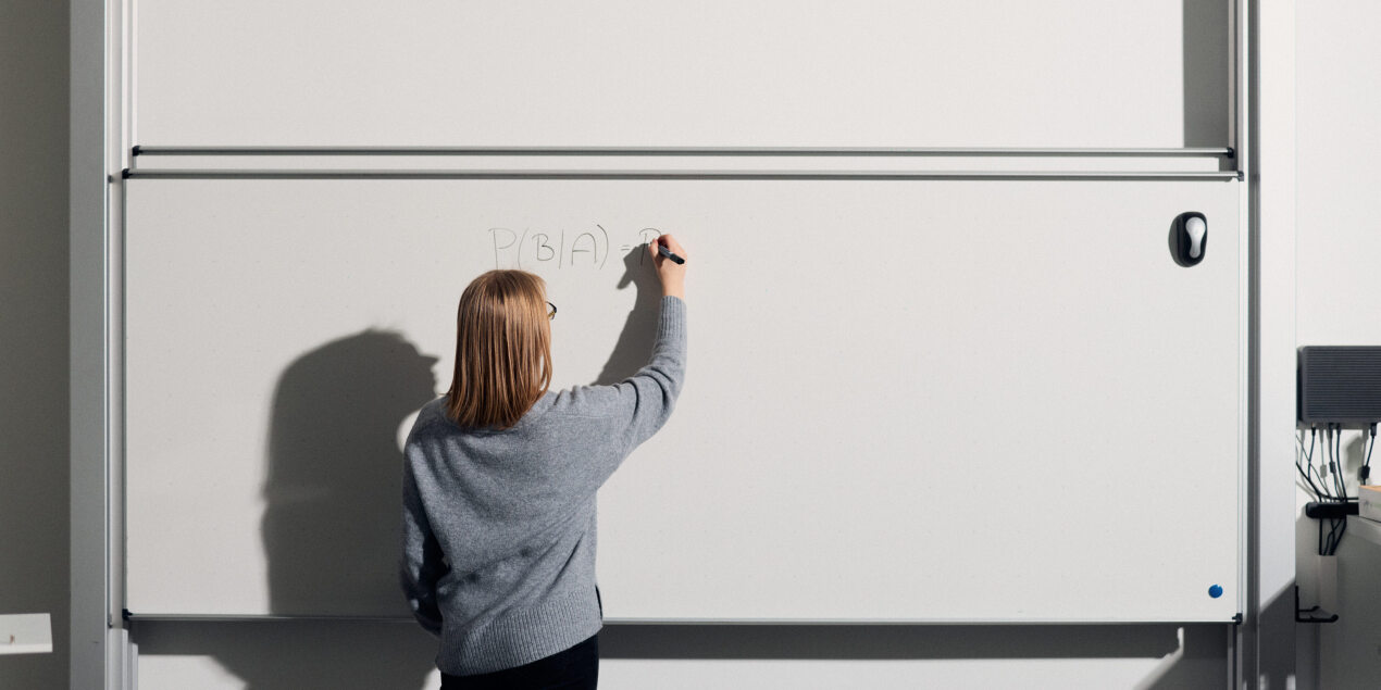 Chiara Freitag schreibt Formeln an ein Whiteboard