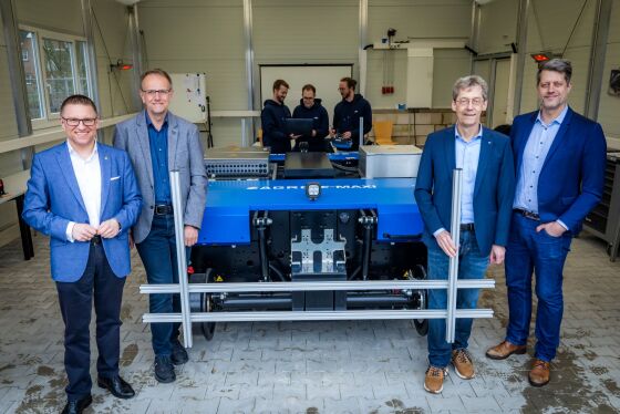 vier Personen stehen neben dem Fahrzeug und drei Personen stehen hinter dem Fahrzeug