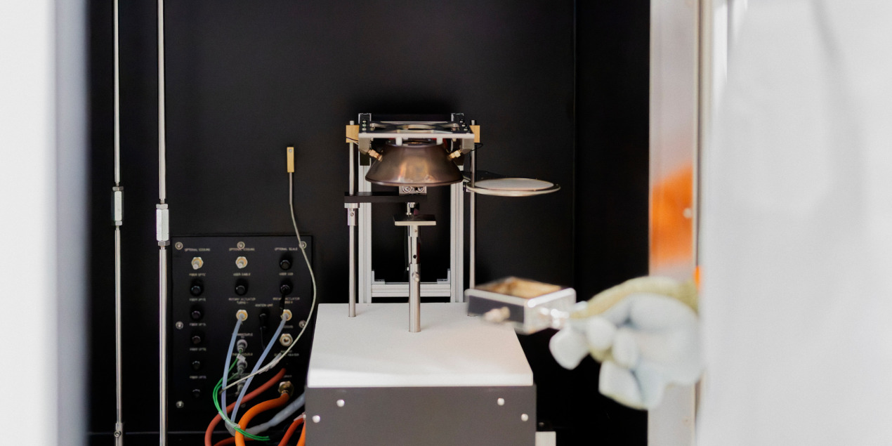 Eine vorbereitete Holzprobe wird in der Rauchdichtemesskammer unter dem Heizelement platziert.