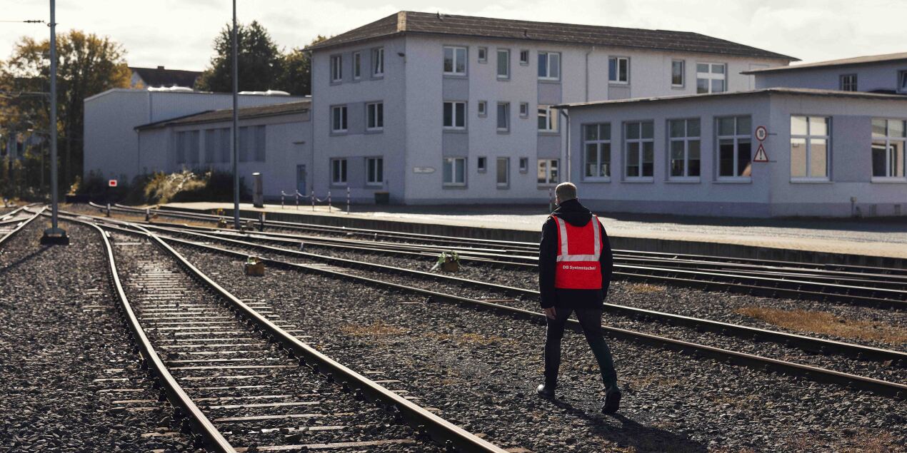 Ein Mensch mit Warnweste geht an Gleisen entlang