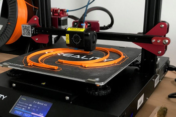 Auf einem 3-Drucker wird eine orangene Stirnhalterung gedruckt.