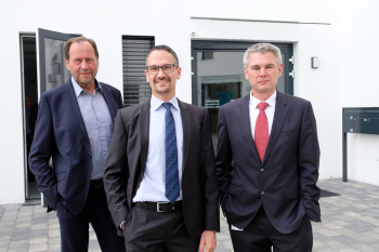 Drei Männer stehen vor einem Gebäude