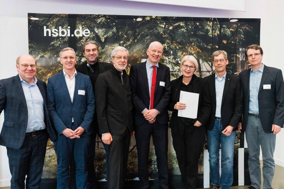 7 Männer und 1 Frau stehen nebeneinander