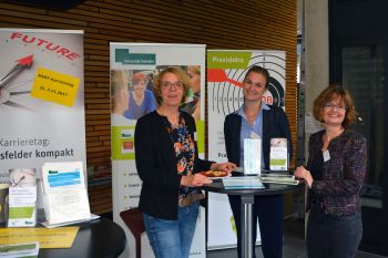 Drei Damen am Stehtisch vor verschiedenen Rollups