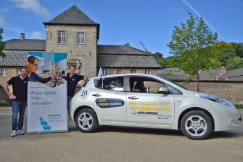 Die beiden Teinehmer stehen mit ihren Elektroauto vor dem schloss.