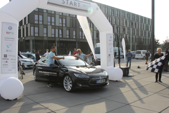 Jens Ohlemeyer und Jutta Kleinschmidt stehen neben einem Elektro-Auto an der Startlinie der e-CROSS GERMANY Rallye.