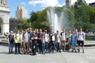 Eine Personengruppe steht vor einem Brunnen.