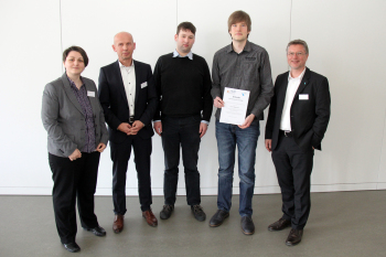Gruppenfoto von fünf Personen, eine Frau. Preisträger Simon Bekemeier hält eine Uhrkunde in der Hand.