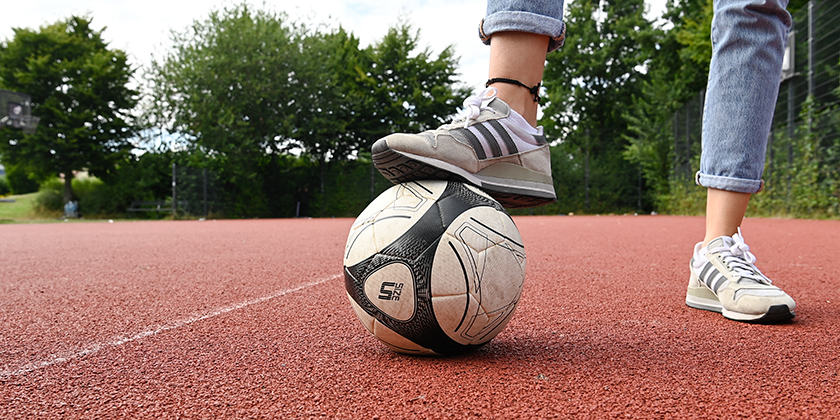 Eine Frau steht mit ihrem Fuß auf einem Fußball.