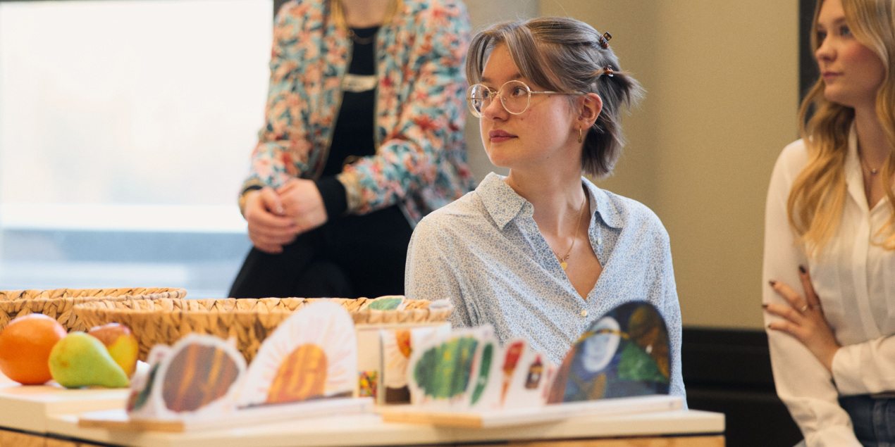 Eine Frau sitzt an einem Tisch, auf dem Obst und Gemüse liegen
