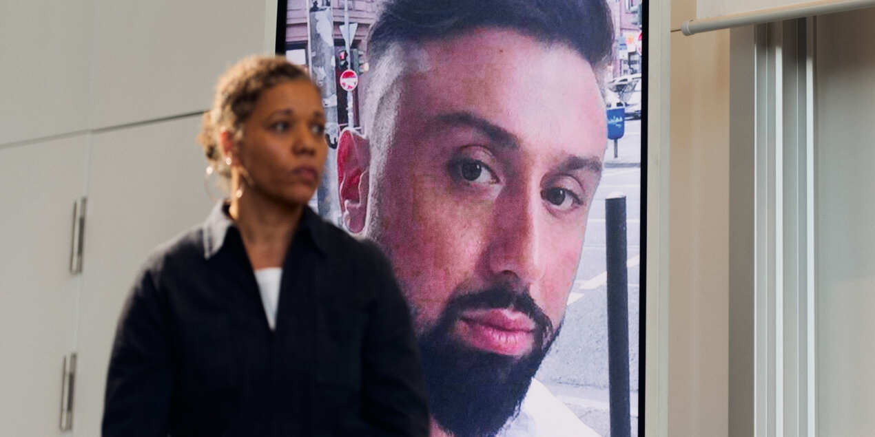 Foto: Eine Frau steht auf der Bühen im Hintergrund sieht man das Porträtfoto eines Mannes