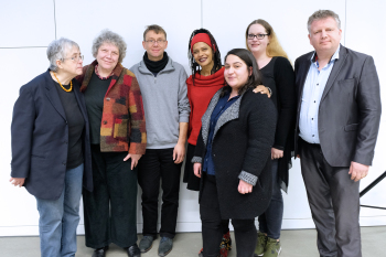 5 Frauen und zwei Männer stehen vor einer weißen Wand