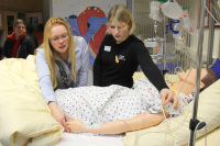 Die Studierenden der Gesundheits- und Krankenpflege demonstrierten zur feierlichen Laboreinweihung Übungen an den Pflegestationen. Hier zeigen zwei Studentinnen die technische Ausstattung der Übungspuppe im Krankenhausbett.