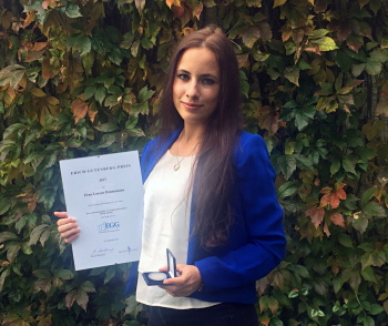 Porträtfoto einer jungen Dame im Grünen mit Urkunde und Medaille