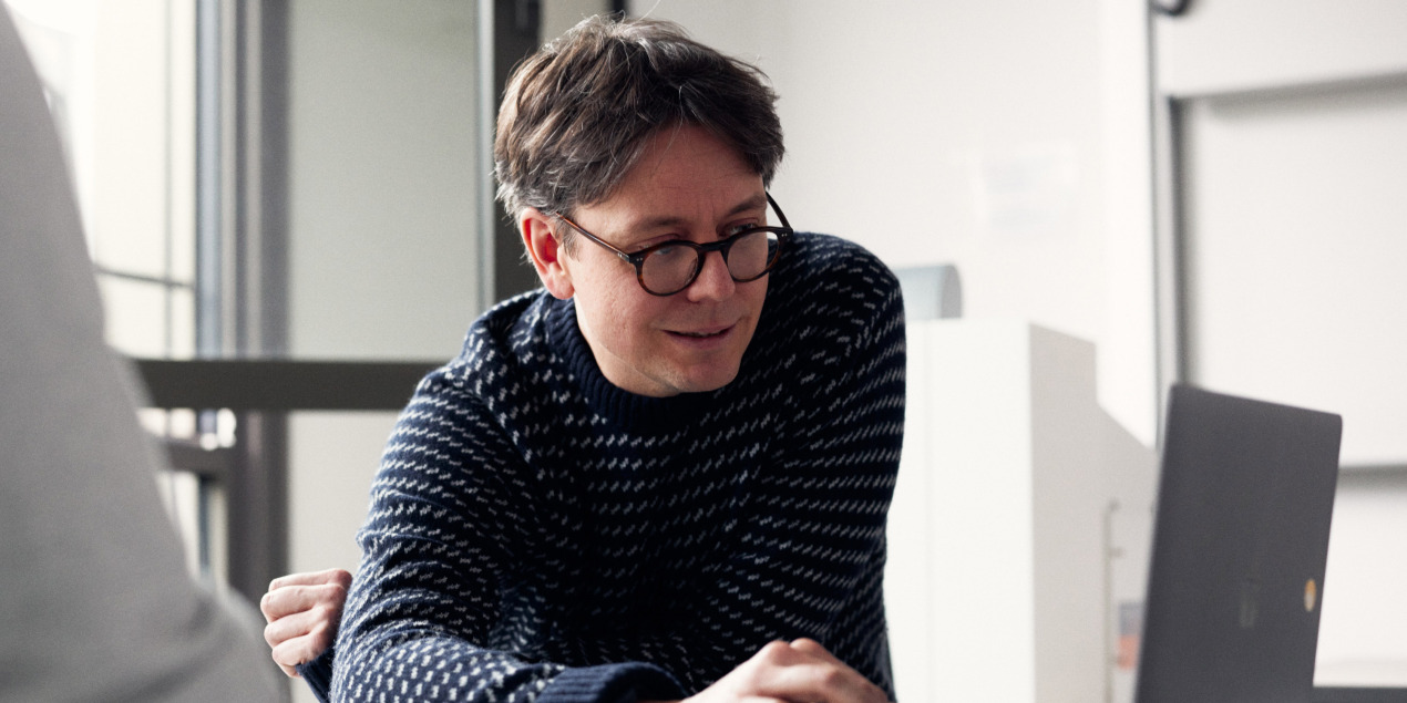 Gerrit Hirschfeld schaut in einen Laptop, der auf einem Tisch steht