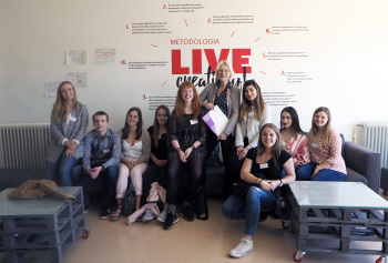 Studentinnen mit Dozentin auf einem Sofa sitzend in die Kamera schauend