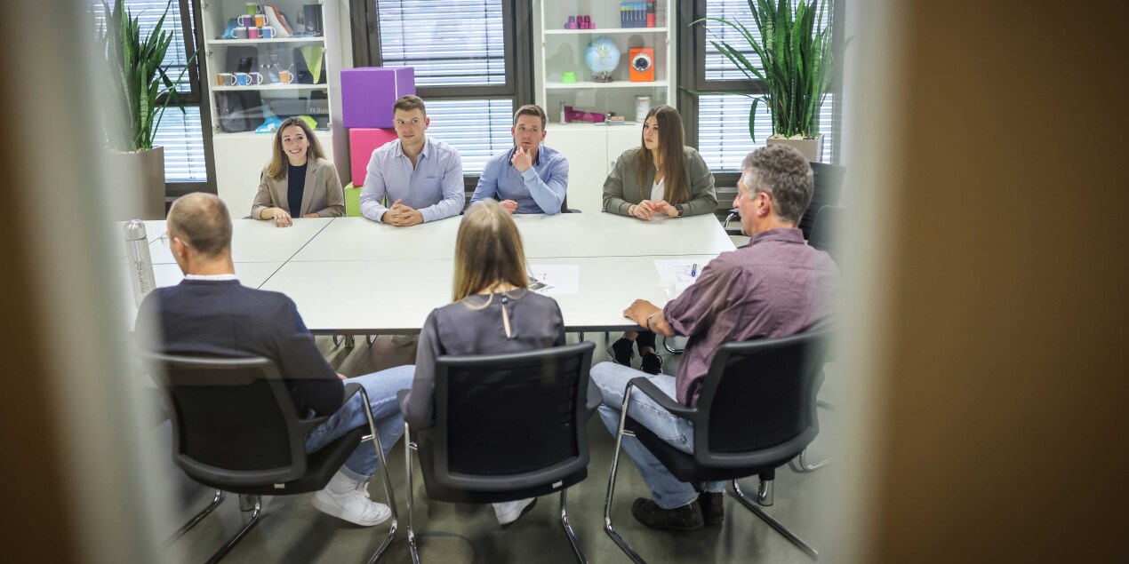 Die Arbeitsgruppe sitzt an einem Seminartisch und bespricht sich