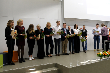 Zeh Menschen stehen auf der Bühne des Audimax und halten Urkunden und Blumen in den Händen