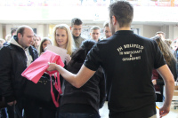 Ein Tutor gibt eine pinke Jute-Tasche an eine Erstsemesterstudentin.