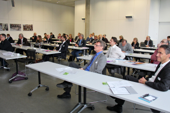Die Teilnehmerinnen und Teilnehmer sirzen an Tischen im Konferenzsaal.