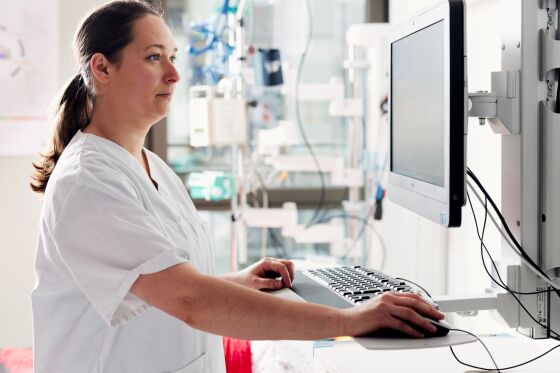 Eine Pflegefachfrau steht im Skills Lab und schaut etwas im Computer nach